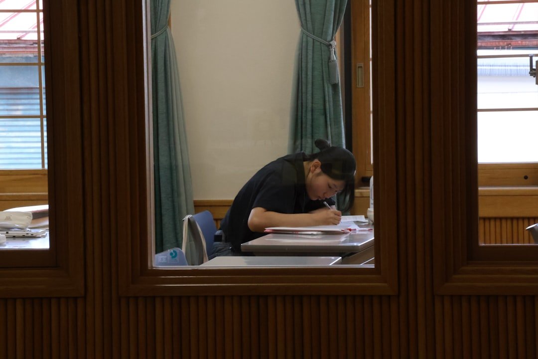 A student writing notes at a desk in a library