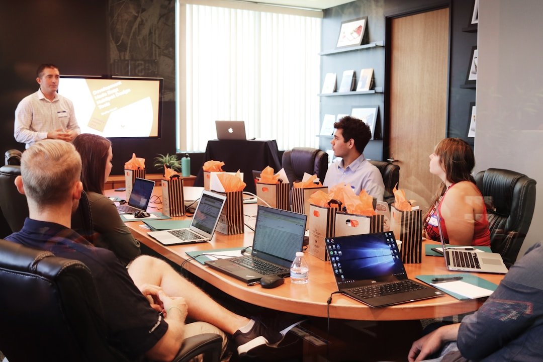 a presenter demonstrating one of the best ai presentation maker free tools to a small team gathered around laptops in a meeting room