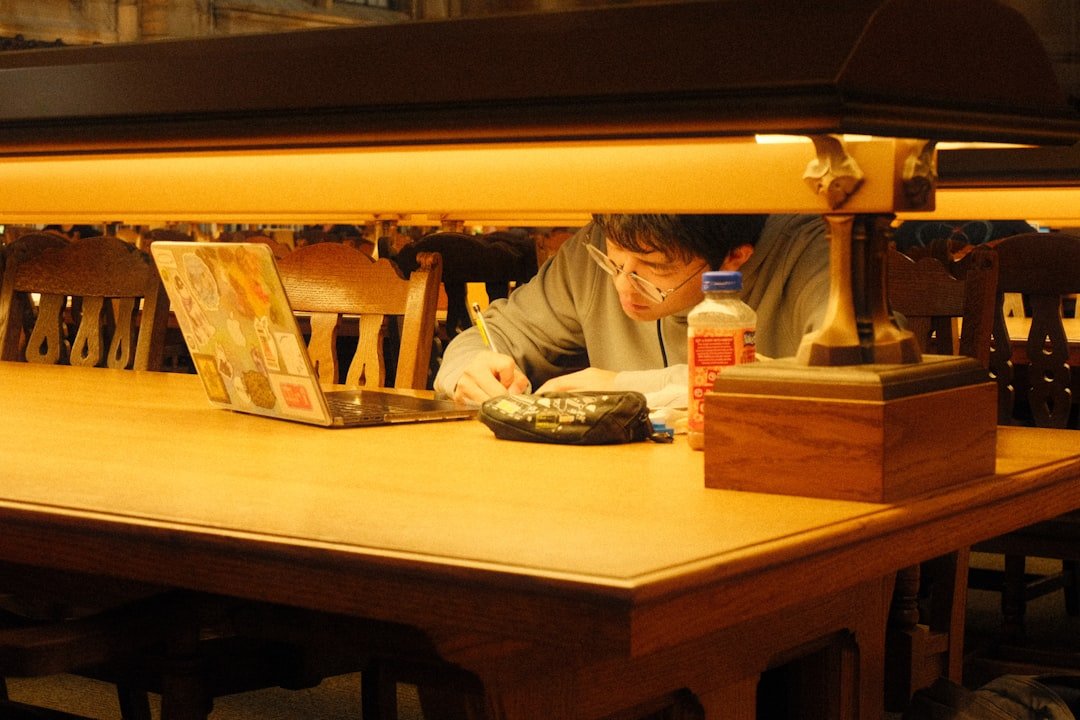 A student researching at a library table with a laptop, the kind of research task where Perplexity AI and ChatGPT are commonly compared