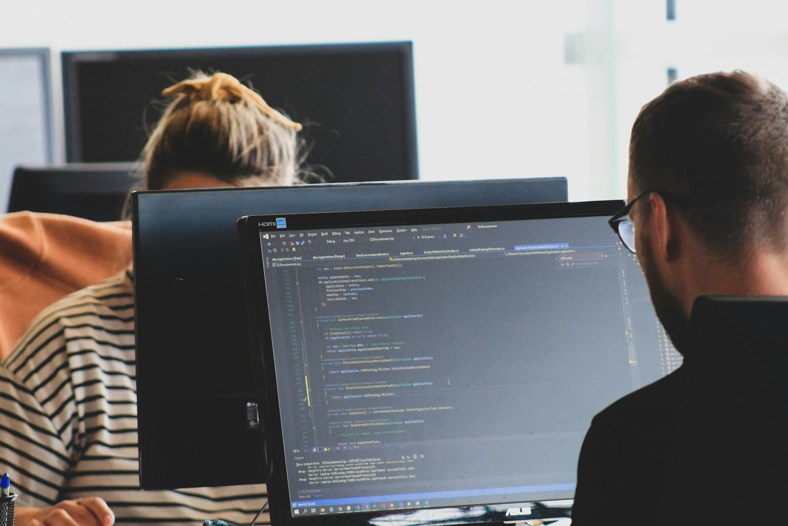 two developers reviewing code on monitors in an office