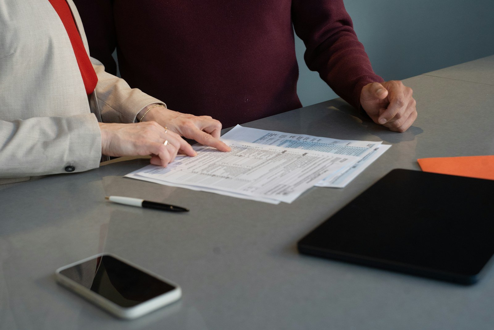 two people reviewing printed documents across a desk