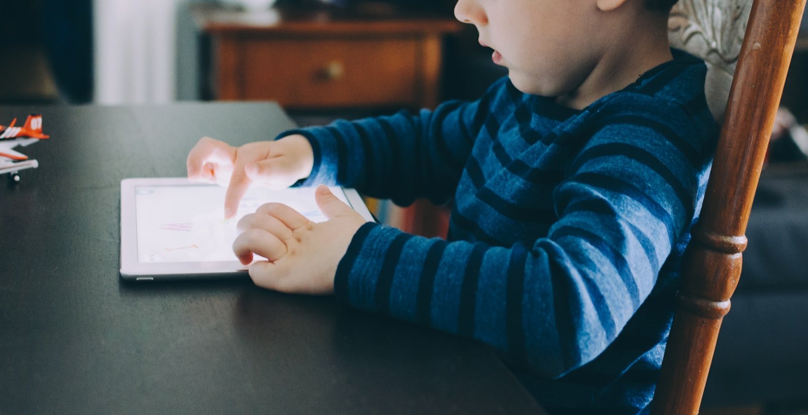 a young child using a tablet at a table