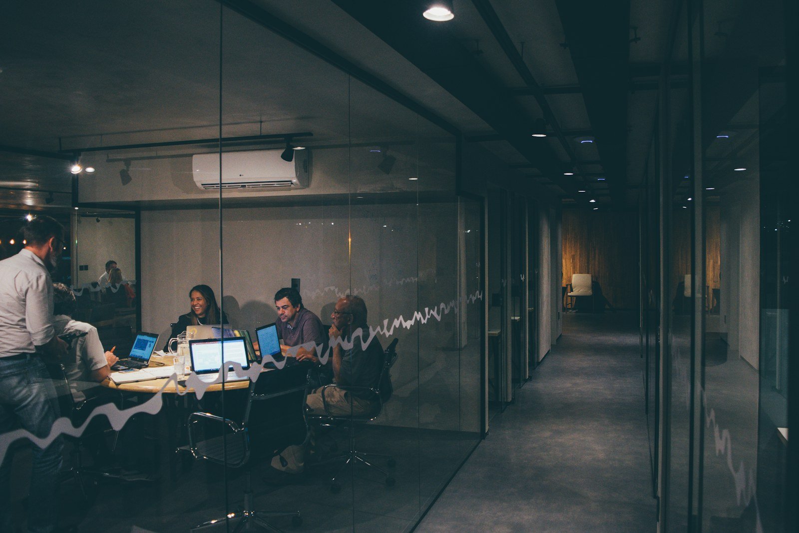 a team meeting seen through the glass wall of an office room