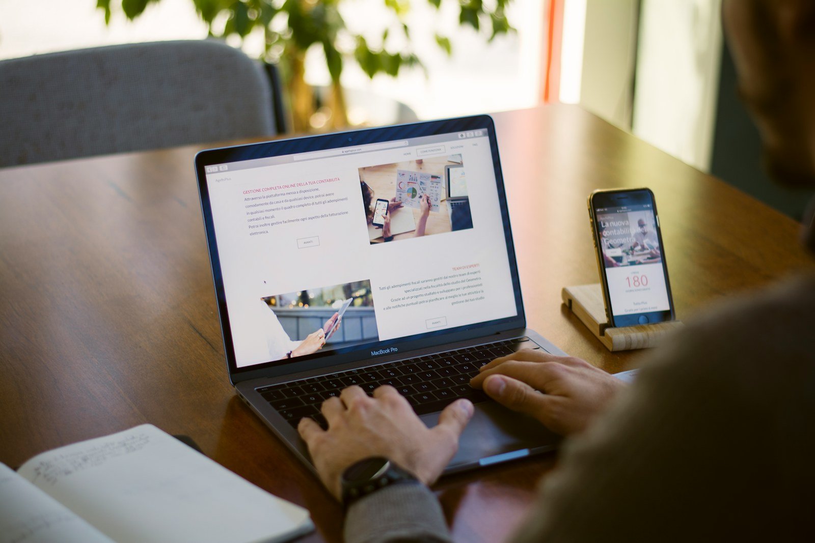 a person browsing a website on a laptop with a phone beside them