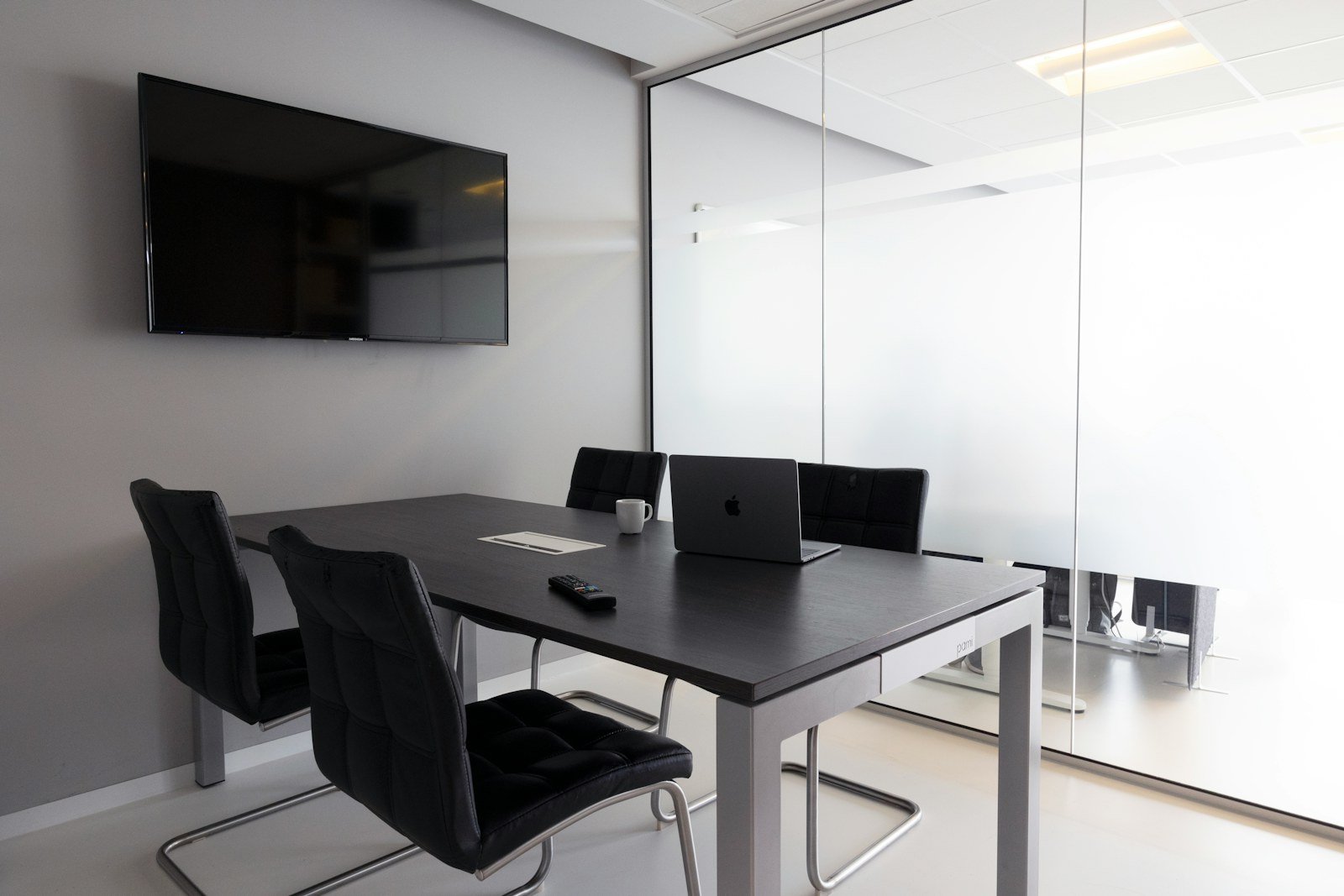 an empty meeting room with a wall screen and laptop on the table