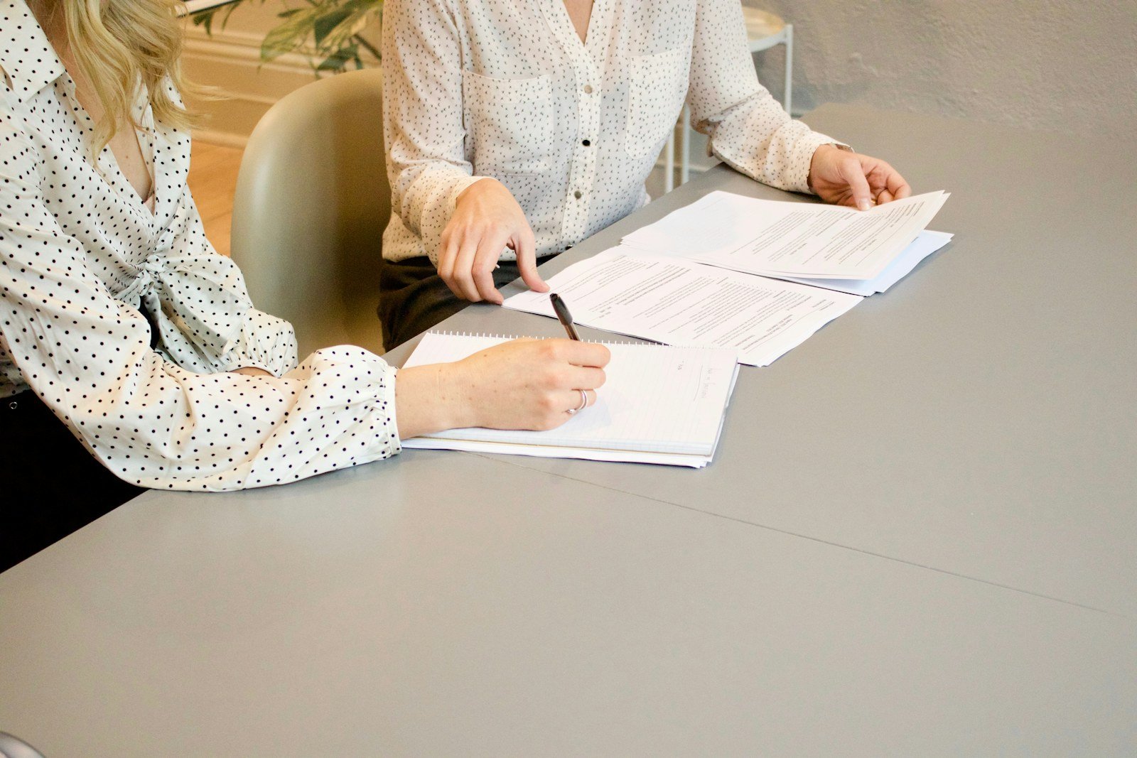 two people reviewing and signing financial paperwork at a table