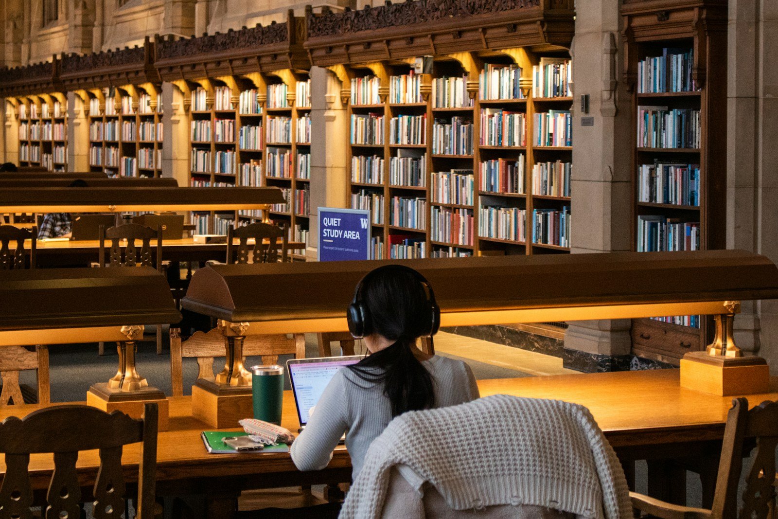 a student studying with a laptop at a long library table