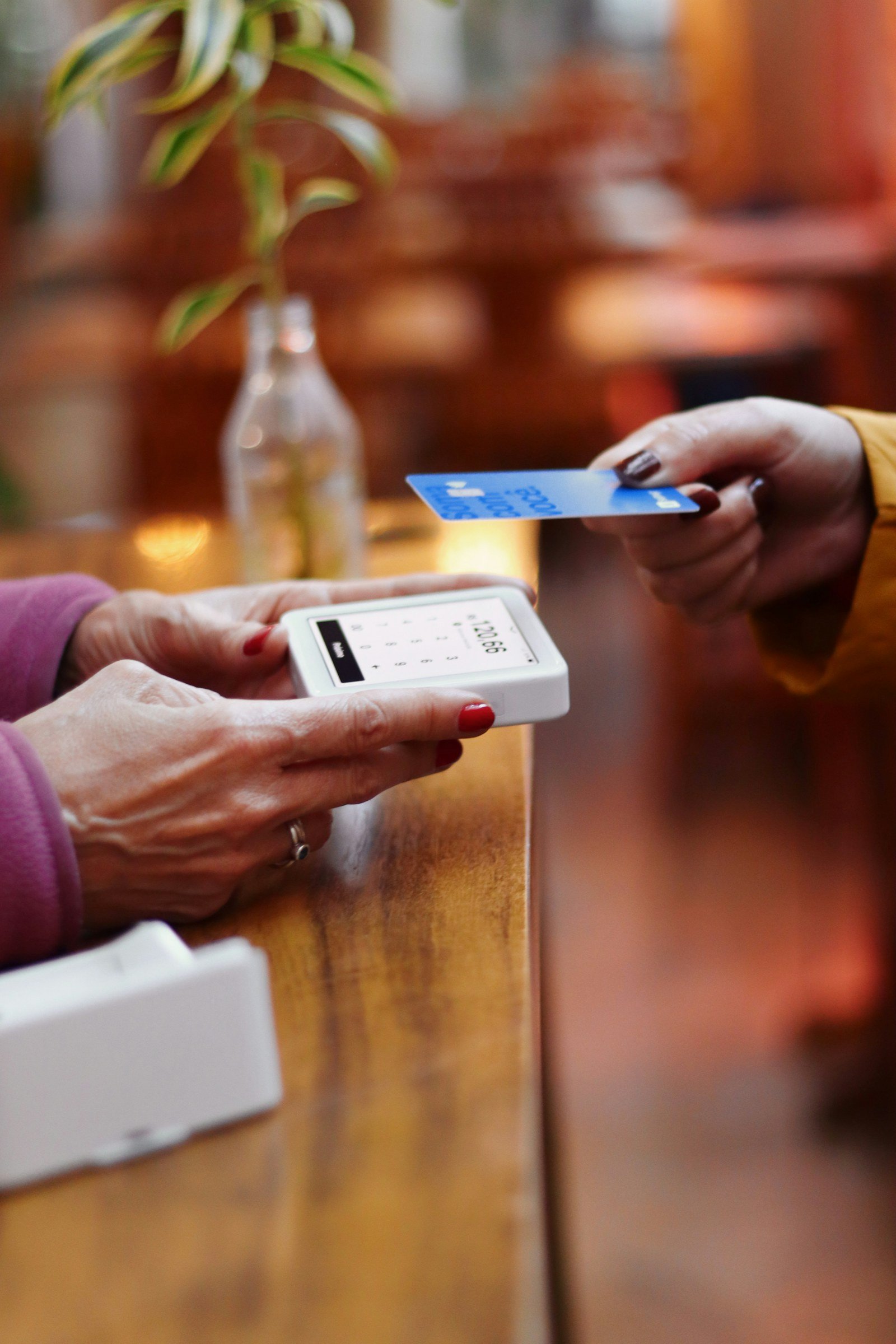 a customer handing a bank card across a cafe counter to a card reader