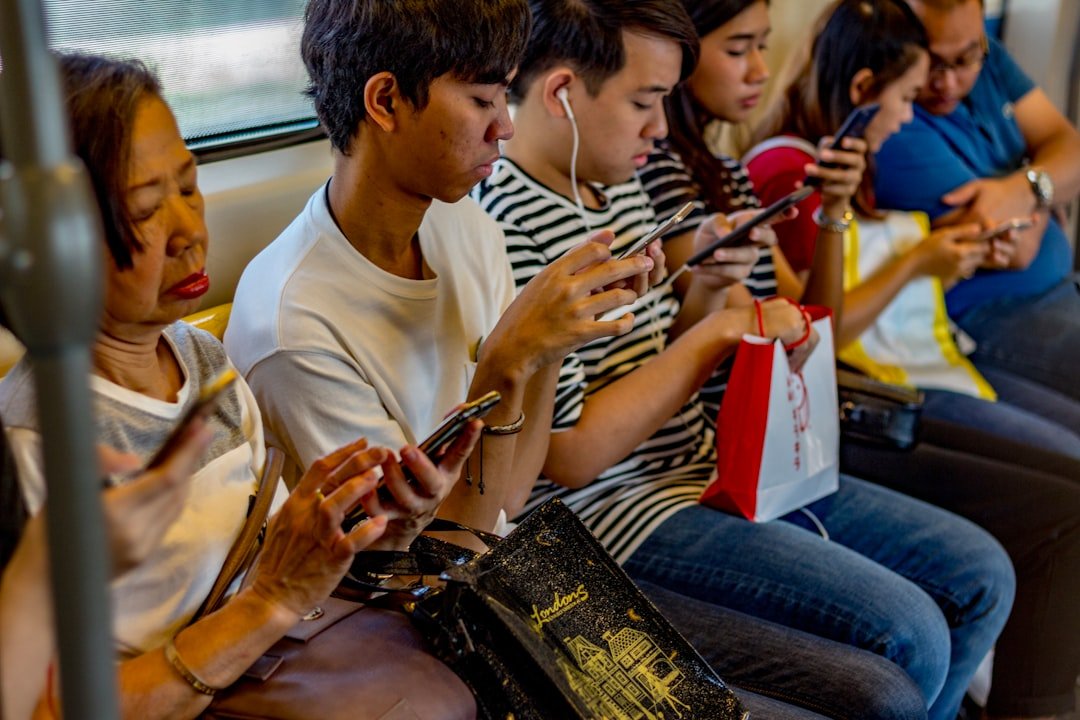 a row of transit passengers all using messaging apps on their phones